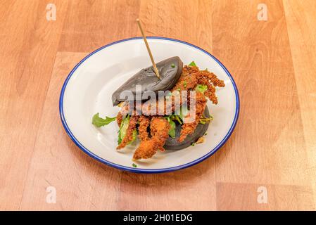 Bao de farine noire avec de la viande de crabe battue en tempura avec des feuilles d'arugula Banque D'Images