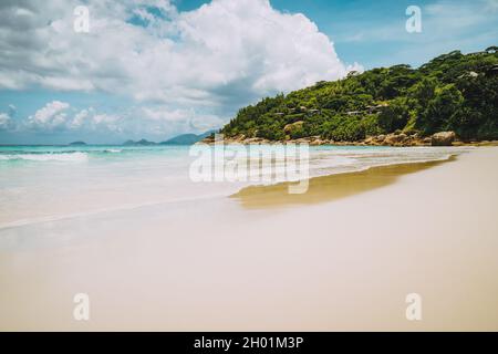 Belle longue plage de sable de petite Anse à l'île de Mahé, Seychelles.Immenses nuages pluvieux dans le ciel.Vacances vacances recréatives Banque D'Images