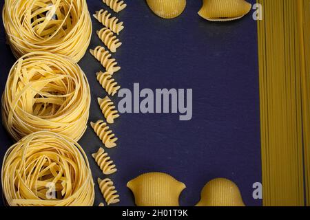 Papier peint à pâtes assorti.Mélangez les pâtes, les spaghettis, les cornes, les spirales et les coquillages sur fond bleu avec un espace de copie Banque D'Images