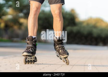 Jambes de sexe masculin sur patins noirs en ligne dans une rue piétonne Banque D'Images