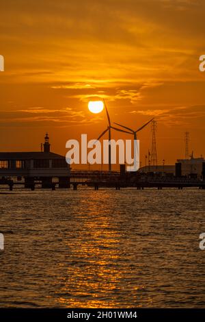 Éoliennes sur les docks de Tilbury depuis la promenade de Gravesend au coucher du soleil.Se reflète sur la Tamise. Banque D'Images