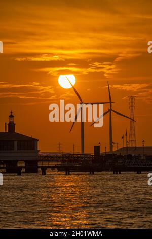 Éoliennes sur les docks de Tilbury depuis la promenade de Gravesend au coucher du soleil.Se reflète sur la Tamise. Banque D'Images