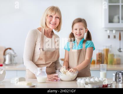 Portrait de sourire caucasien granny et petite-fille ayant plaisir à cuisiner à la maison cuisine ensemble.Bonne dame aimante et petite fille pâtisserie tarte Banque D'Images