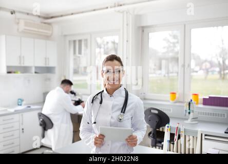 Portrait d'une femme médecin confiante avec un comprimé en laboratoire Banque D'Images