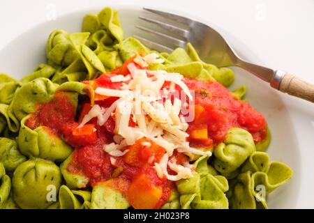 Un gros plan du fromage samorza sur la sauce tomate et les pâtes de fagottini vertes Banque D'Images