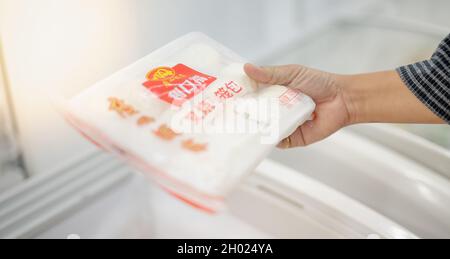 WUHAN, CHINE- SEP 22, 2021: Main de femme en gros plan en choisissant la collation qui est prête à manger sur l'étagère au supermarché local. Banque D'Images