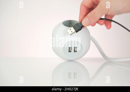 Adaptateur USB.prise avec connecteur USB.Les mains incluent le câble USB dans le chargeur.gadgets et la technologie.Douille blanche carrée et mains femelles avec Banque D'Images