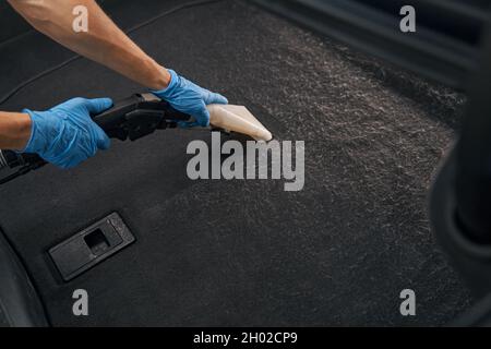 Travailleur professionnel utilisant un aspirateur humide pour l'interio de voiture sale Banque D'Images