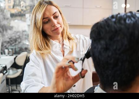 Coiffeur ciblé qui tond les cheveux de sa cliente Banque D'Images