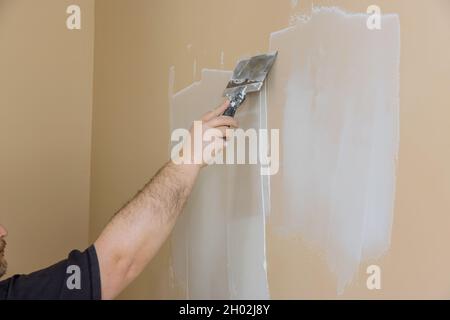 Pendant la rénovation de la chambre, un employé a enduit le mur en plaques de plâtre Banque D'Images