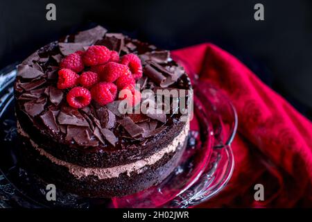 Délicieux gâteau au chocolat est photographié libre, avec de la crème au chocolat , copeaux de chocolat, et garnie de framboises rouges frais Banque D'Images