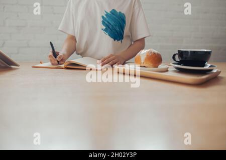 Jeune femme écrivant dans un carnet dans un café Banque D'Images
