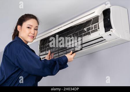 technicien de maintenance féminin pour la dépose du filtre à air du climatiseur pour le nettoyage Banque D'Images