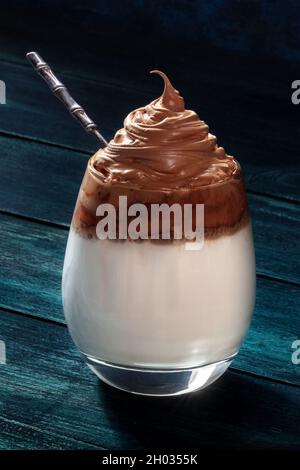 Café froid Dalgona avec une cuillère, sur fond bleu foncé.Milk shake coréen Banque D'Images