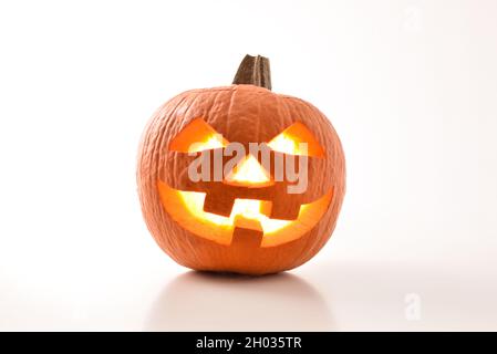 Citrouilles d'halloween sculptées et illuminées préparées pour les fêtes reflétées sur une table blanche et un fond blanc isolé. Vue avant. Comp. Horizontale Banque D'Images