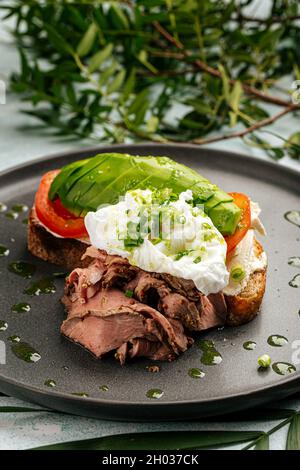 Sandwich à l'avocat avec rôti de bœuf et œuf poché Banque D'Images