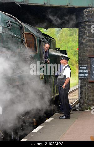 Le chauffeur de train de la locomotive à vapeur 9F de l'ex British Railways 92214 discute avec le maître de la gare de Loughborough, Great Central Railway, août 2021 Banque D'Images