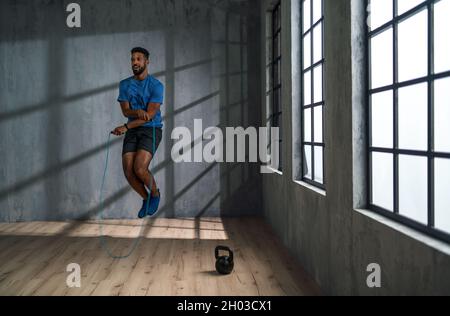 Jeune sportif afro-américain utilisant la corde de saut à l'intérieur, concept d'entraînement. Banque D'Images