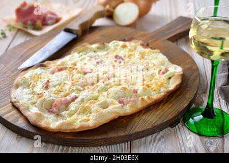 Tarte d'Alsace avec oignons, bacon fumé et fromage munster chaud au four, servie avec du vin blanc alsacien Banque D'Images