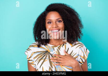 Photo de la peau douce et foncée impressionnée femme habillée Imprimer chemisier sourire bras poitrine isolé teal couleur fond Banque D'Images