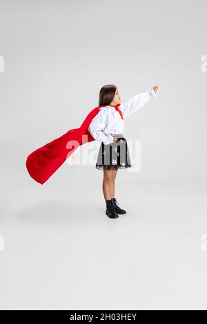 Portrait de la belle petite fille caucasienne portant le cap rouge debout isolé sur fond blanc studio avec copyspace pour l'annonce Banque D'Images