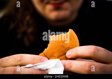 Munich, Allemagne.1er octobre 2021.Un homme est assis dehors sur un banc pour manger un hamburger.Crédit : Finn Winkler/dpa/Alay Live News Banque D'Images