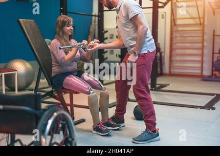 Entraîneur personnel aidant une femme handicapée dans son entraînement Banque D'Images