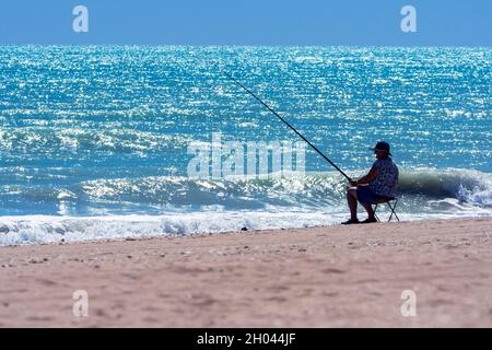 Pêcheurs isolés pêchant en mer depuis une chaise sur la plage, Eighty Mile Beach, Australie occidentale, Australie occidentale, Australie Banque D'Images