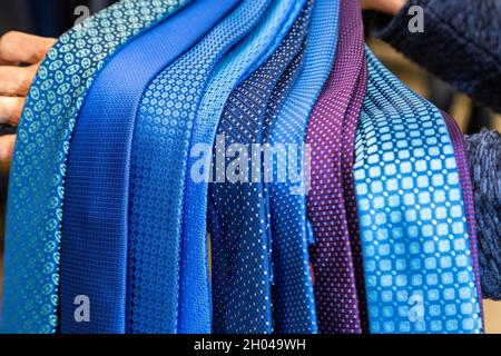 Un grand ensemble de cravates bleues, bleues et violettes est à portée de main.Des attaches de ventilateurs sombres magnifiquement agentées. Banque D'Images