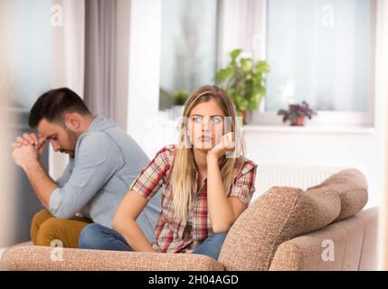 Jeune couple ayant des problèmes dans la relation, arguant et se sentant triste.Salon avec canapé Banque D'Images