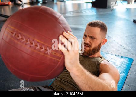 Portrait d'un jeune homme sportif barbu qui s'entraîne dans la salle de gym avec un ballon de sport.Vue de dessus.Gros plan.Le concept de forme physique. Banque D'Images