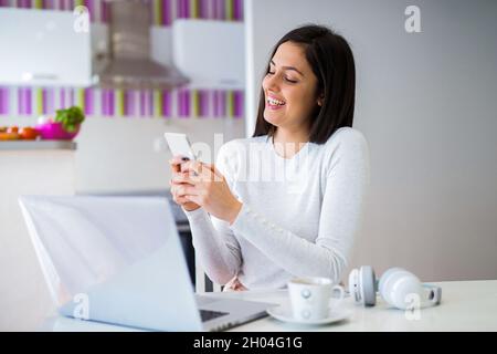 Une jeune fille étudiante prend la pause après avoir été clouée et assise devant un ordinateur et tenant le téléphone dans ses mains. Banque D'Images