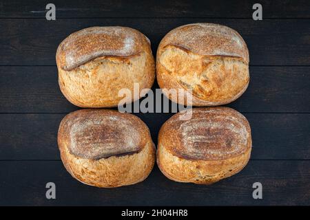 Le pain de blé artisanal se trouve à la surface d'une couleur sombre, en arrière-plan, vue de dessus. Banque D'Images