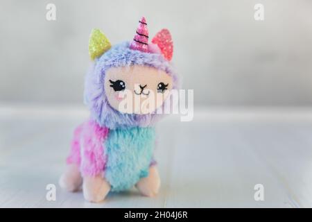 licorne en peluche colorée sur fond de bois blanc.Jouet pour enfants célèbre et populaire. Banque D'Images