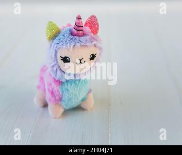 licorne en peluche colorée sur fond de bois blanc.Jouet pour enfants célèbre et populaire. Banque D'Images