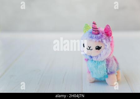 licorne en peluche colorée sur fond de bois blanc.Jouet pour enfants célèbre et populaire. Banque D'Images