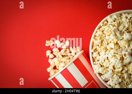 Gobelets en papier avec pop-corn sur fond rouge. Banque D'Images