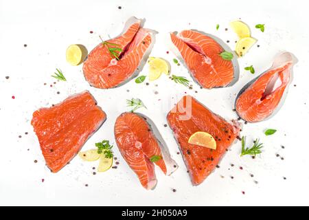 Ensemble de viandes fraîches prêtes à cuire des steaks de saumon cru, des tranches de poisson rouge avec du sel et des épices, sur fond de table blanc vue du dessus de l'espace de copie Banque D'Images
