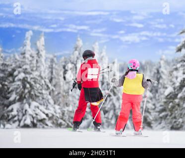 Groupe d'enfants apprenant à skier sur la pente avec un instructeur.Ciel bleu et firs blancs en arrière-plan Banque D'Images