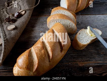 Baguette française sur table en bois avec couteau et beurre.Couper en morceaux et servir avec un couteau de beurre. Banque D'Images