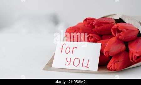 Un bouquet de tulipes rouges et une carte avec inscription pour vous sur fond blanc.Fleurs en papier artisanal.Livraison de fleurs d'anniversaire Banque D'Images