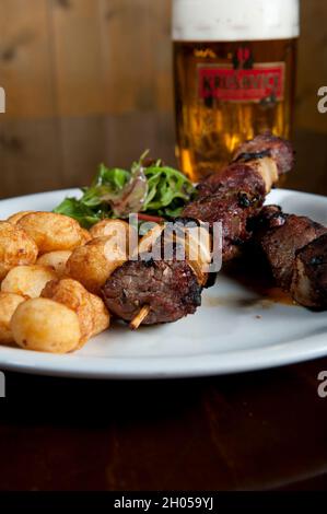 Mini pommes de terre cuites au four, brochette d'agneau et un verre de bière froide Banque D'Images