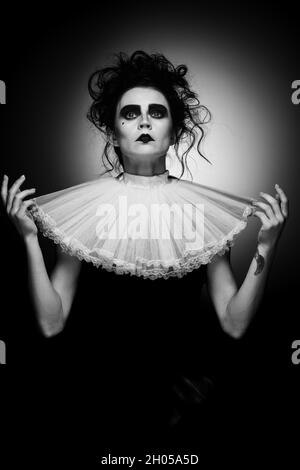 Image rognée en noir et blanc d'une femme artistique portant un costume de fête d'Halloween avec un maquillage sombre isolé sur fond noir Banque D'Images