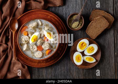 Soupe de seigle fermentée à polir Zurek avec kielbasa blanc poli traditionnel ou saucisse avec marjolaine, œufs durs servis sur un bol en argile avec un bois Banque D'Images