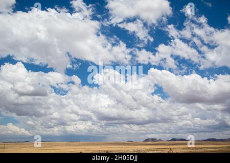 Un ciel nuageux sur un paysage plat et ouvert avec une route menant à la distance. Banque D'Images