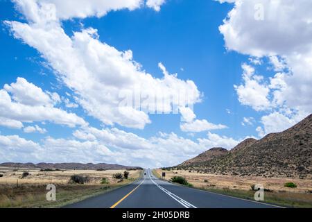 Un ciel nuageux sur un paysage plat et ouvert avec une route menant à la distance. Banque D'Images