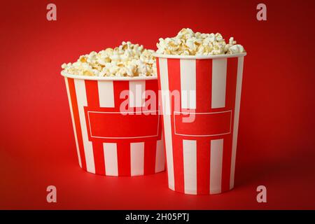 Gobelets en papier avec pop-corn sur fond rouge. Banque D'Images