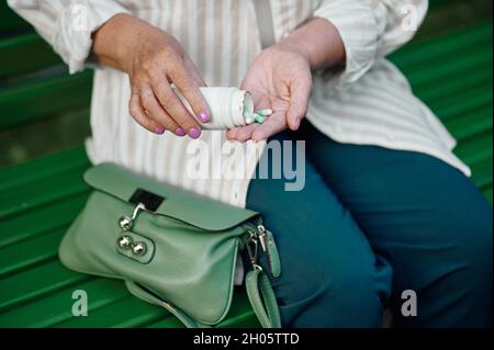 Granny prend des pilules de son sac dans le parc d'été Banque D'Images