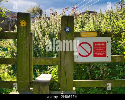 Un panneau d'avertissement rouge et blanc sur une bordure du chemin de la côte de Northumberland avertit les marcheurs du danger des lignes aériennes.Panneaux de direction de la trajectoire Banque D'Images