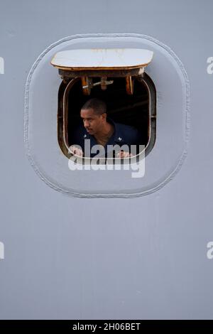 Norfork, États-Unis.08 octobre 2021.Un marin de la marine américaine regarde d'un hublot alors que le navire de transport amphibie de classe San Antonio USS San Antonio arrive à homeport après un déploiement de six mois avec la 5e flotte le 8 octobre 2021, à Norfolk, en Virginie.Crédit : MC1 Joshua D. Sheppard/États-UnisNavy/Alamy Live News Banque D'Images